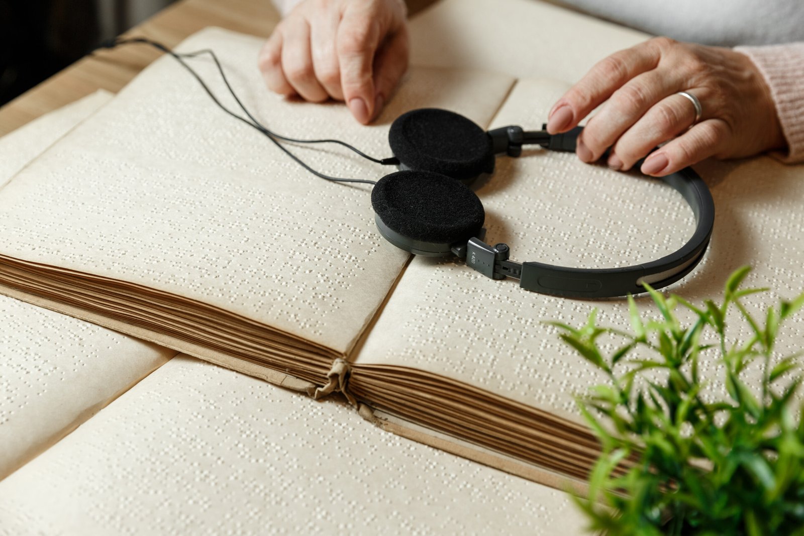 Headphones resting on an open braille book, symbolizing the synergy of audio and tactile information for accessibility.